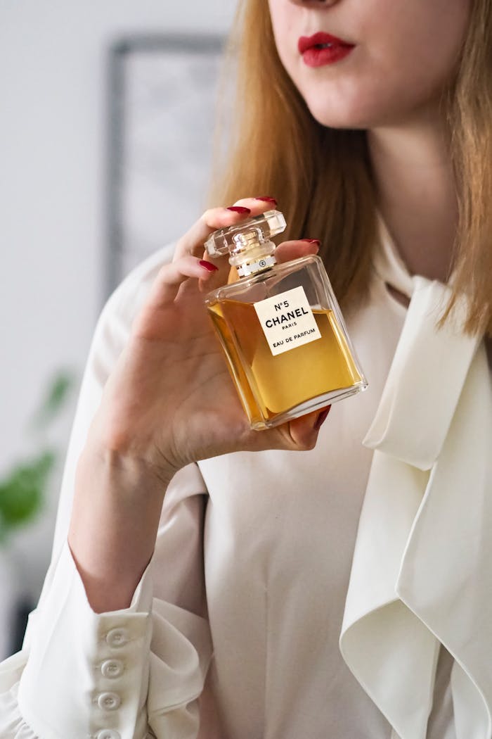 services-04 Close-up of a woman holding a Chanel No. 5 perfume bottle, showcasing elegance in Paris.
