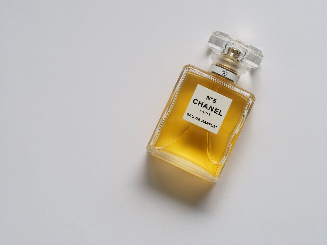 services-03 Elegant eau de parfum bottle with luxurious golden liquid on a minimalistic white background.